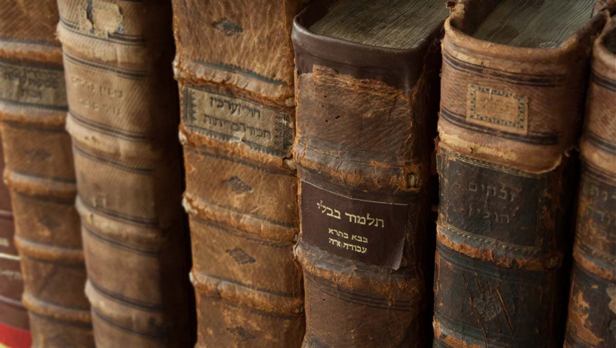 An old copy of the Talmud on a shelf with other Jewish books